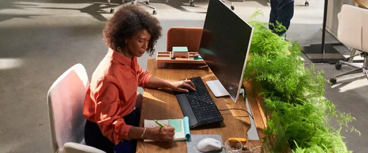 Dame som sitter ved skrivebord i ett åpnet kontorlandskap