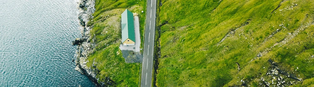En vei med ett hus som likker ned til vannet
