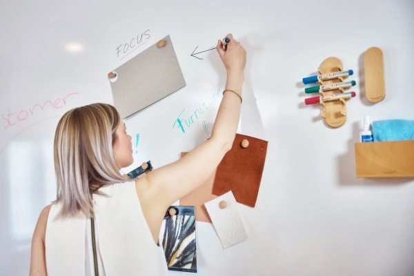 En person som skriver på ett whiteboard med Wood serie produkter på tavlene.