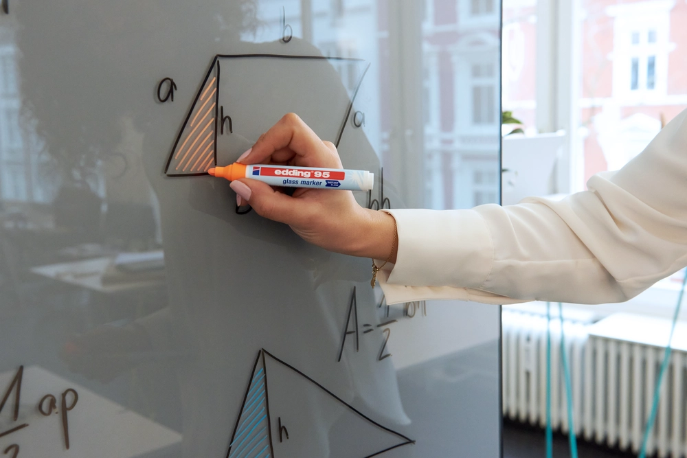 Skriver matteoppgave på tavle med Edding merkepenn for glass