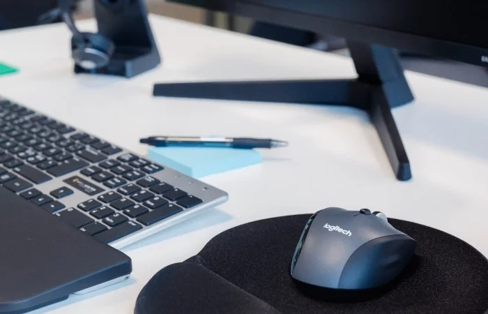 En kontorpult med tastatur, mus, musmatte, blyant og en skjerm