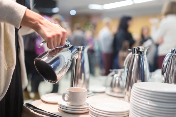 Person som heller fra en kanne opp i en porselen kopp