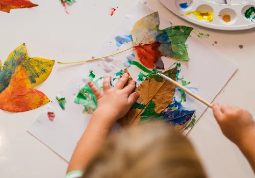 Ett barn som maler på blader og ark