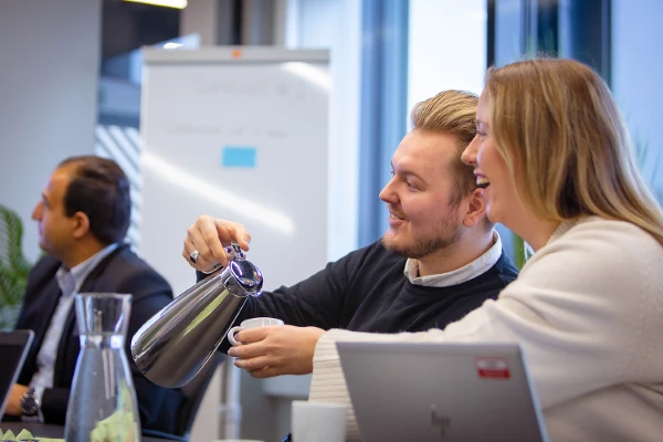 2 personer på et møte, hvor en fyller koppen til den andre