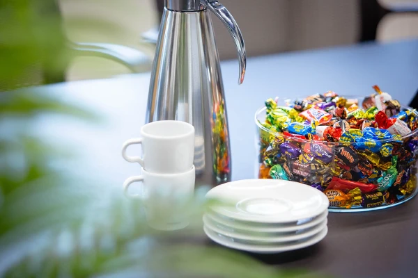 Kaffe kanne, kopper, asjetter og en bolle med twist på ett bord