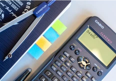 Kalkulator på ett bord med en notatblokk ved siden av