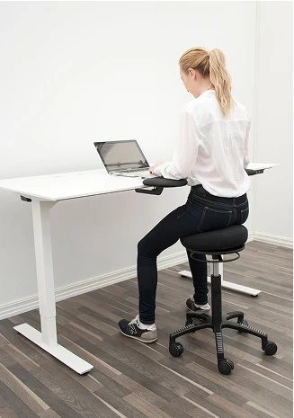 Person som sitter på en gøy stol uten rygg ved et skrivebord