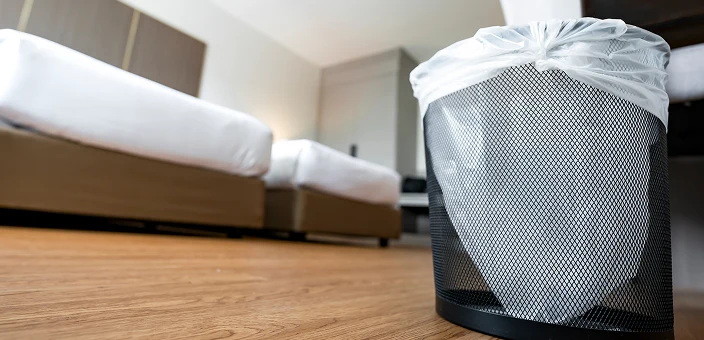 Ett hotelrom med 2 senger og en søppelbøtte