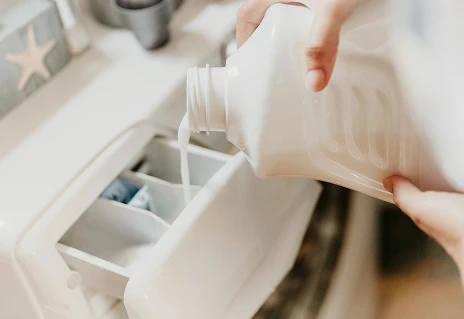 En person som heller vaskemiddel i en vaskemaskin