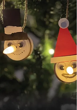 2 hjemmelaget julepynt på ett juletre. melkekartong kork med nissehatt