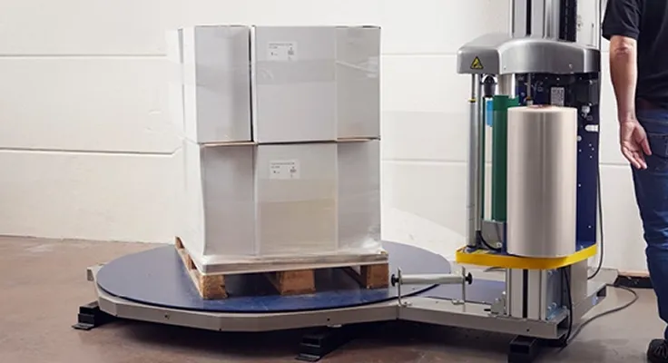 En person som pakker in en pall med strekkfilm