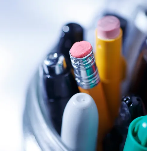 Nærbilde av ett glass med kulepenner, blyanter og tusjer