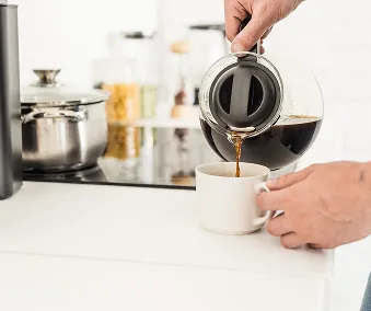 En person som heller kaffe fra en kaffekanne