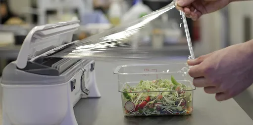 En person som bruker en wrapmaster til å dekke over en oppbevaringsboks