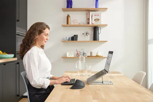 En person som sitter med en ergonomisk mus foran en laptop i et kontormiljø