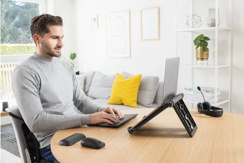 En person som skriver på ett tastatur foran en laptop på en laptop stativ