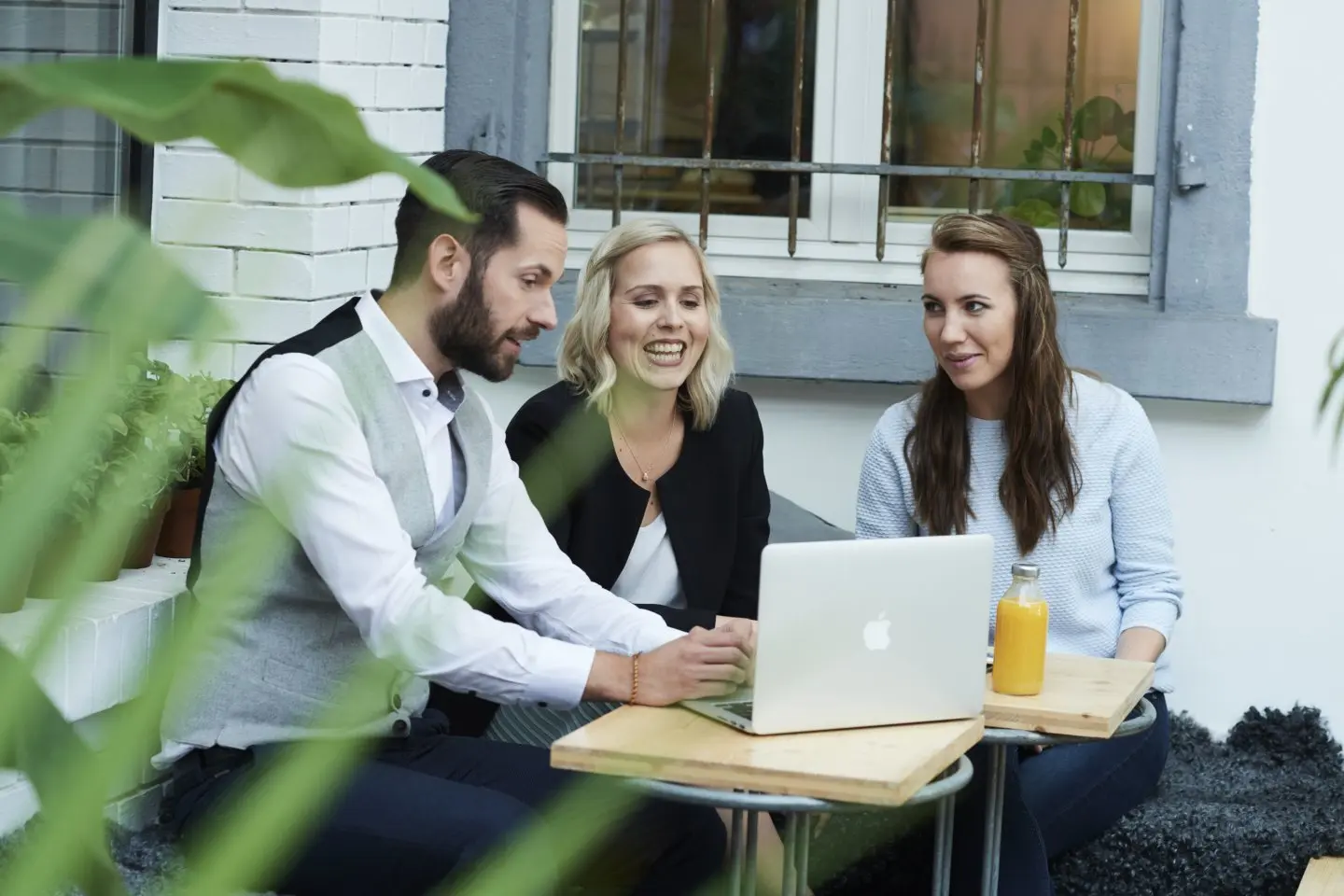 Kollegaer har møte utendørs med laptop og drikke