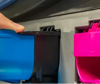 En person som tar ut en tonerkassett fra en skriver