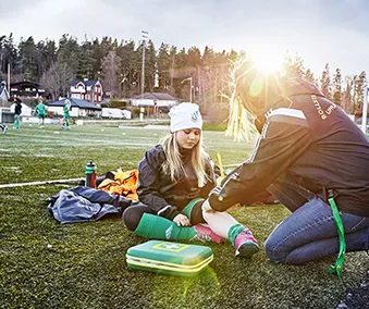 En person som bruker førstehjelpskoffert og hjelper ett barn