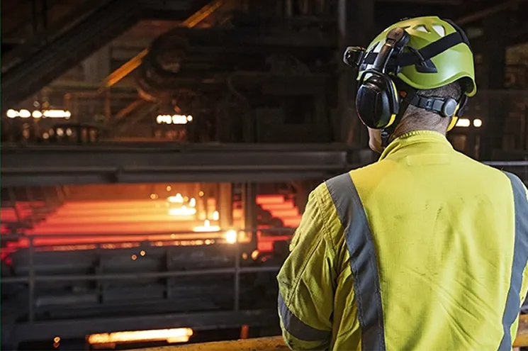 En person med verneutstyr på seg som ser på ett smelteanlegg