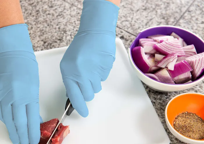 En person med engangshansker som kutter en biff