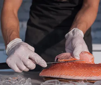 Bilde av en person med engangshansker på som filerer en fisk