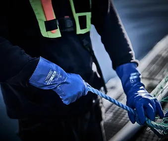 En person som holder i ett blått tau med hansker