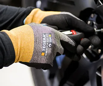 En person med hansker som holder i ett verktøy