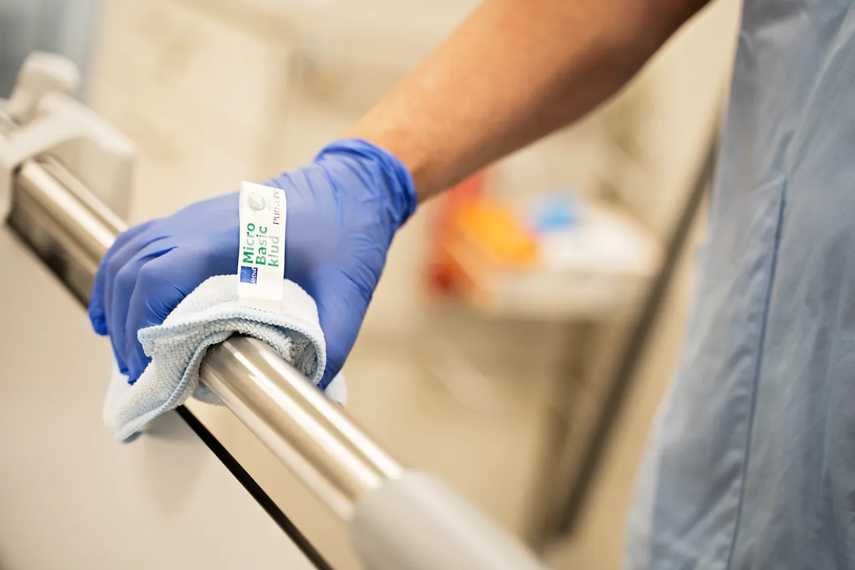 En person med engangshansker som vasker ett gelender