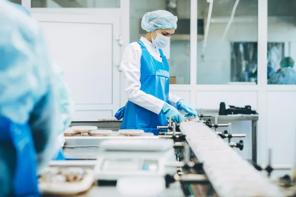 En person på en arbeidsplass i maske, hårnett og engangsbekledning