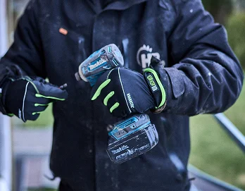 En person med arbeidshansker som holder en drill