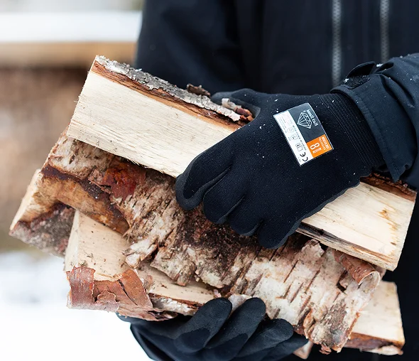 En person med hansker som holder vedkubber