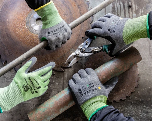 2 par hender med TEGERA® hansker som holder diverse metall biter. En holder en blikksaks