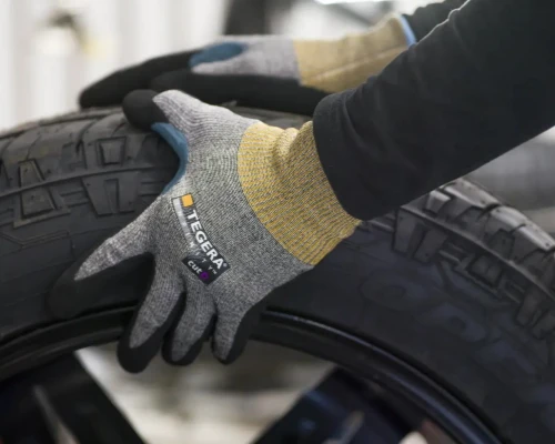 En person som som ruller ett dekk med TEGERA® hansker på hendene