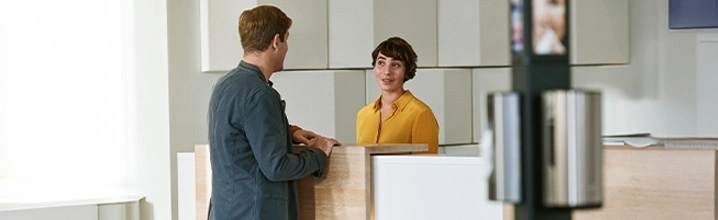 En person som som snakker med en annen i ett resepsjons området med en dispenser fra Tork i forgrunnen