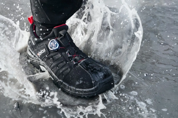 Ben til en person med vernesko som tråkker i en vannpytt