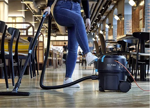 En person som bruker en støvsuger i en kantine
