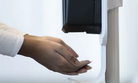 En person som bruker en desinfeksjonsdispenser