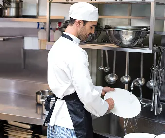 Ett kjøkkenperson som rengjør en tallerken