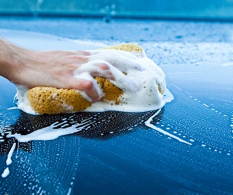En hånd som holder en svamp og vasker en bil