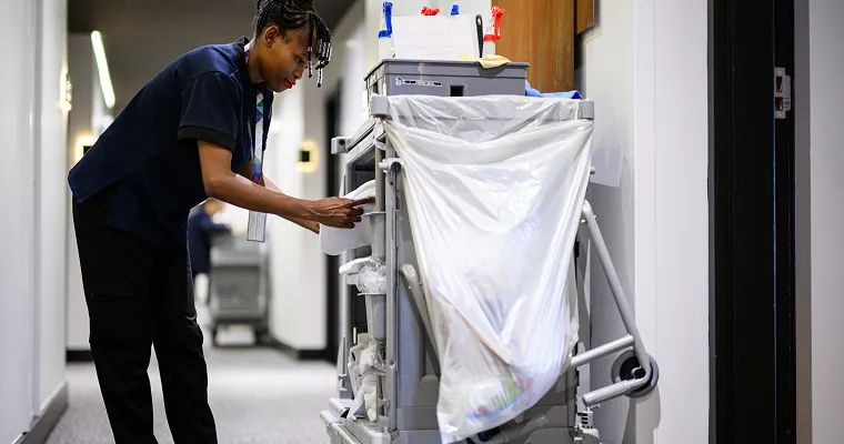 Vaskepersonal som tar noe ut av en rengjøringsvogn