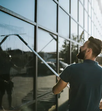 En person vasker ett vindu med svabb