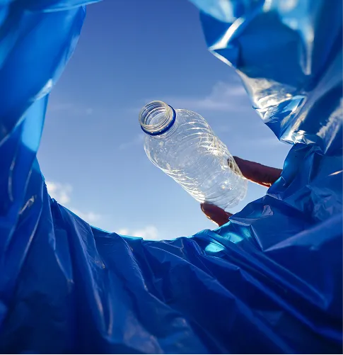 Bilde fra insiden av en blå søppel pose hvor noen kaster en flaske