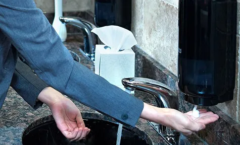 en person som bruker en såpedispenser i et offentlig toalett