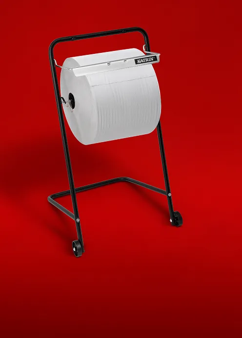 Katrin gulvstativ for tørkerull med stor papirrull mot rød bakgrunn.