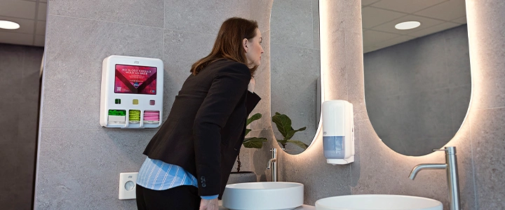 Person ved vask med dispenser på veggen