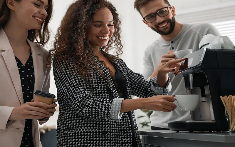 Kolleger bruker kaffemaskin på kontoret