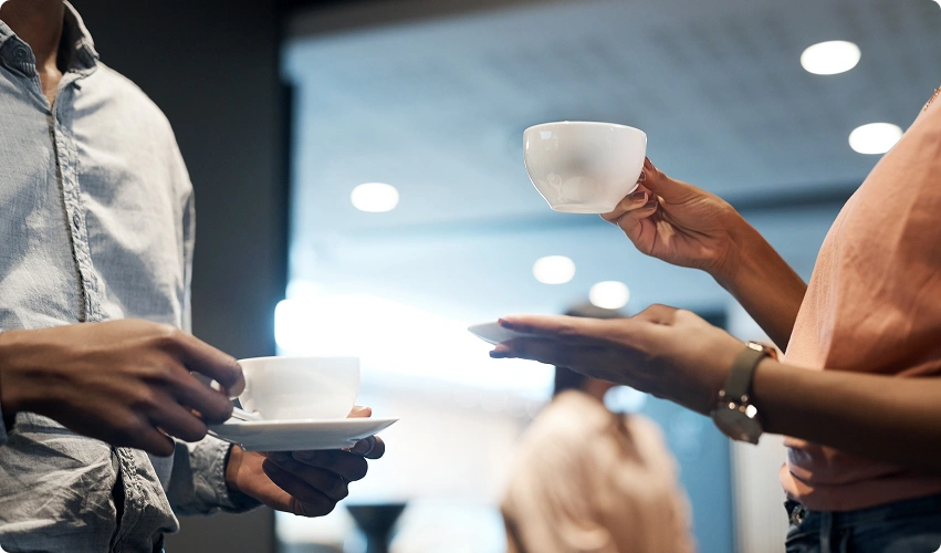 nærbildet av 2 personer som holder i hver sin kopp kaffe på kontoret