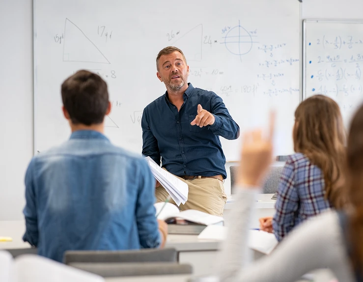 Bilde av en lærer som holder undervisning for elever foran whiteboard tavle
