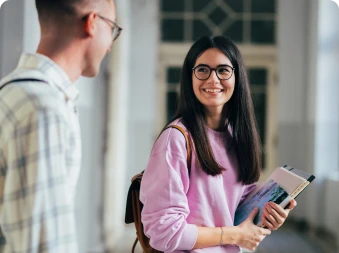 Bilde av 2 studenter i en gang som ser på hverandre og smiler